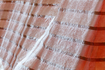 Water cascades over orange, textured surface © schankz