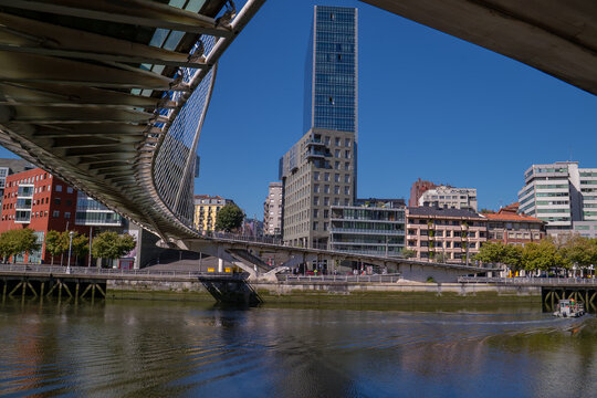 Zubizuri bridge arches over the river with modern buildings defining the urban skyline