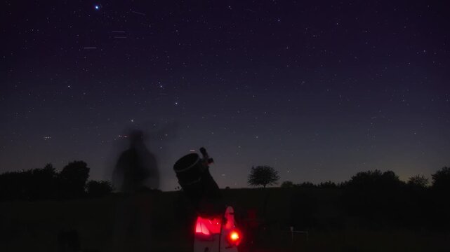 Amateur astronomers observing stars, planets, Moon and other celestial objects with a telescope in nature. Time-lapse video.