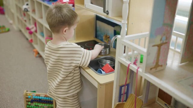 Creative young kid boy pretending to cook in kindergarten nursery