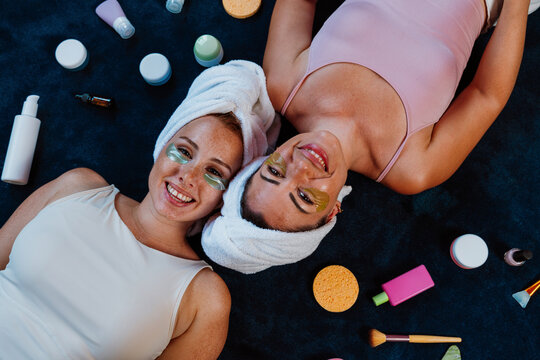 Two happy women lying down, enjoying beauty treatment with under eye patches