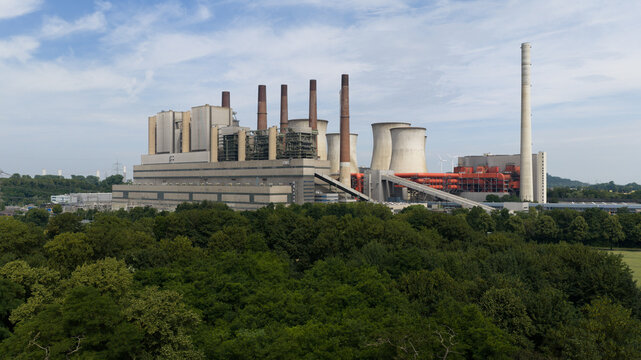 Grevenbroich, Germany - 23 June 2026: Aerial view of the RWE Power AG Kraftwerk Neurath power station with large cooling towers and chimneys rising above the surrounding forest.