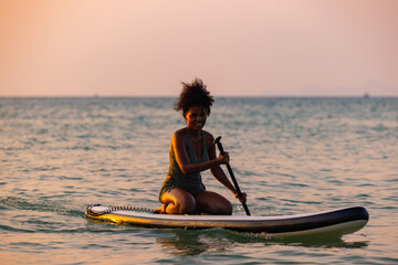 Obraz premium Woman Paddleboarding Silhouette at Golden Sunset Sea