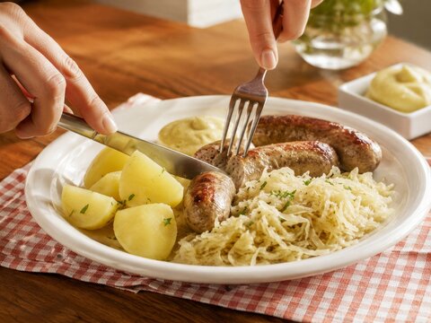 Disfrutar de un plato con salchichas, pur&eacute; de patatas y chucrut en un ambiente acogedor