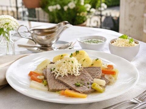 Plato de carne con verduras y salsa en un restaurante al mediod&iacute;a