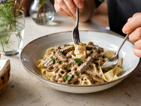 Disfrutar de un plato de pasta con carne y salsa en un restaurante moderno