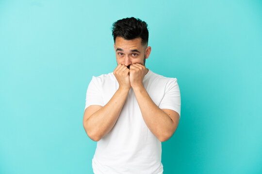 Young caucasian man isolated on blue background nervous and scared putting hands to mouth