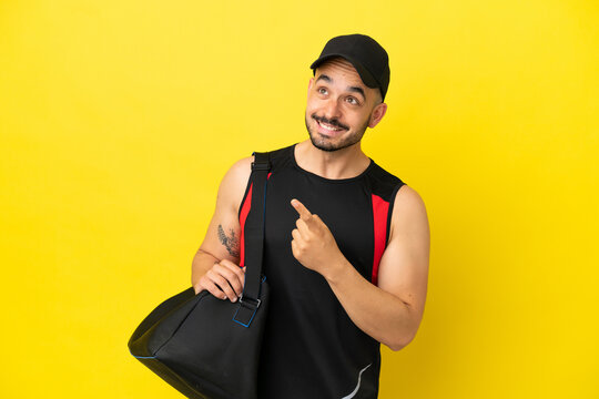 Young sport caucasian man with sport bag isolated on yellow background intending to realizes the solution while lifting a finger up