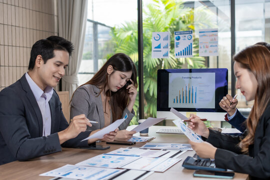 Business team reviewing reports and charts in a modern office meeting room, discussing sales growth, planning strategy, and working together on financial analysis