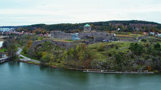 Aerial view of historic stone fortress on riverside hill with autumn forest backdrop