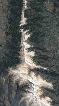 Panoramic shot on mountain ridge covered with snow. Camera is zooming out. Vertical video. Animation based on image by NASA