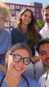 Group of diverse doctors and nurses taking a selfie video outdoors