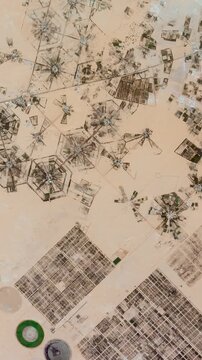 Flying above agricultural landscape in arid area. Camera is zooming out, rotating counterclockwise. Vertical video. Animation based on image by NASA