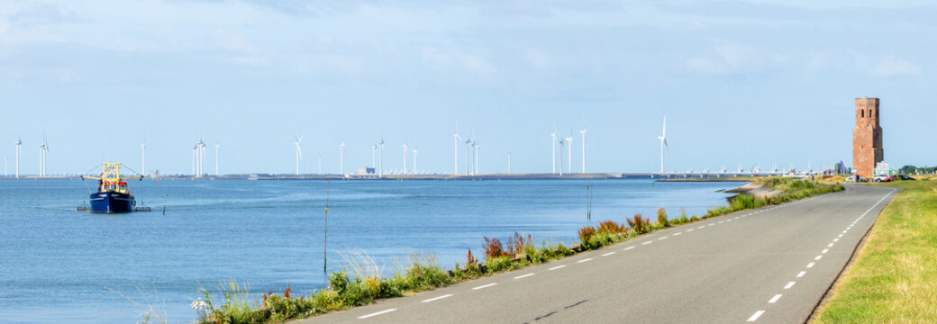 Panoramic view of the Eastern Scheldt estuary near Plompe Toren (Zeeland, Netherlands) with mussel fishing vessel, storm surge barrier and wind turbines
