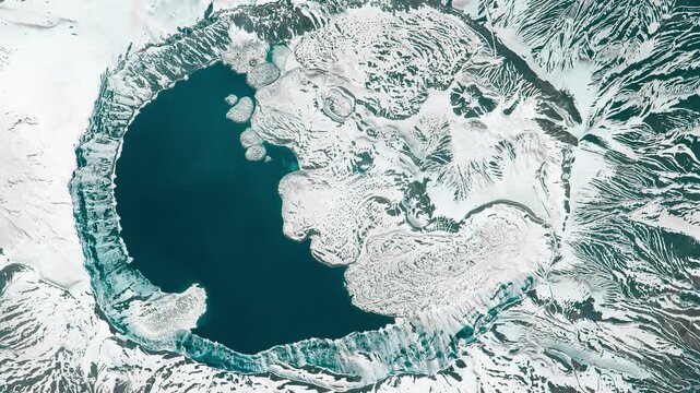 Aerial shot of caldera of volcano covered with snow and filled with water. Camera is moving left. Animation based on image by NASA