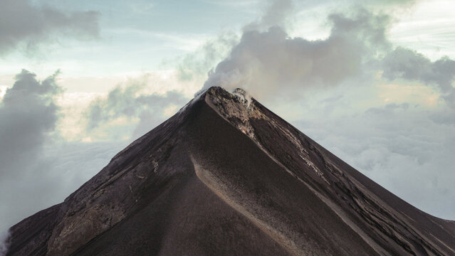 Volc&aacute;n Fuego emits a plume of smoke above the mountains of Guatemala during a period of volcanic activity under clear skies.