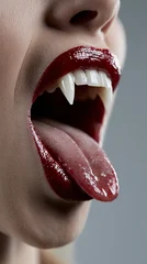 Female mouth opening to reveal sharp vampire fangs, vertical photo featuring spooky Halloween makeup, dramatic close-up and horror fantasy concept © annebel146