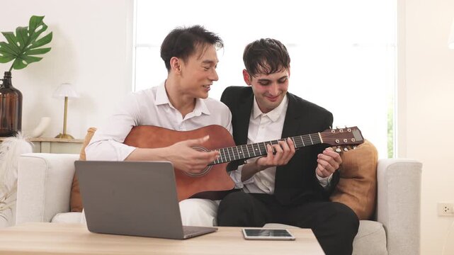 Friends learning guitar with laptop at home