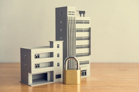 Commercial buildings and padlock on table with white wall background. Asset forfeiture, foreclosure, repossession procedure in court, law enforcement, illegal criminal, bankruptcy and so on concept.