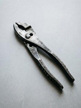 Vintage worn metal slip-joint pliers on a white textured background