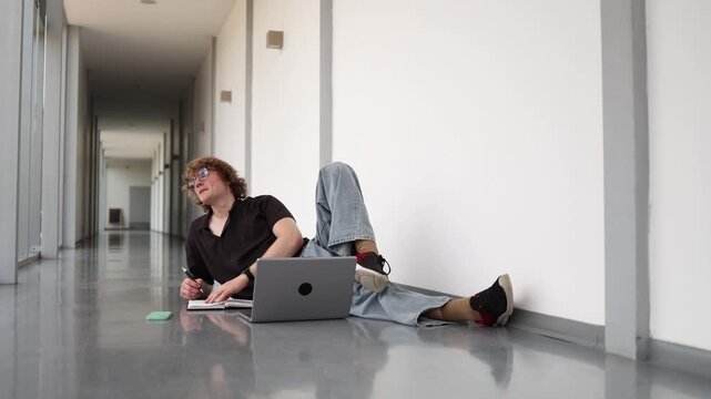 Vertical screen Young software developer studies with laptop and notebook on office floor showing modern IT education coding practice continuous learning and focus