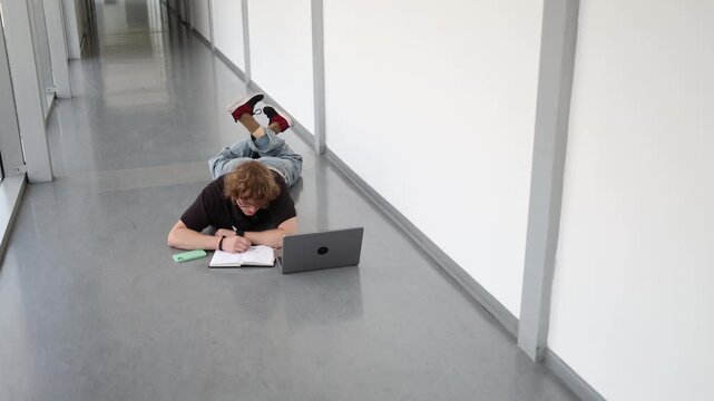 Vertical screen Young man studies on floor with notebook and laptop showing concentration self education productive learning and modern student lifestyle