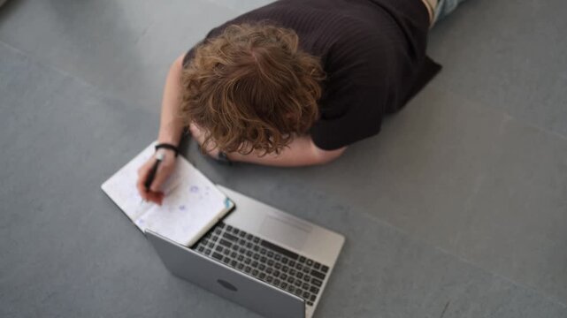Student studies on floor with laptop and notebook proving determination to learn anywhere focused education modern learning persistence and dedication