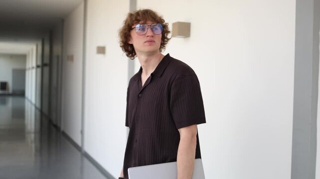 Young office worker leaves workplace carrying laptop after losing job to artificial intelligence reflecting automation career uncertainty and workforce changes
