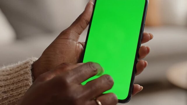A Person Holding a Smartphone with a Bright Green Screen Display, Showcasing Touch Interactions and Digital Engagement in a Cozy Environment