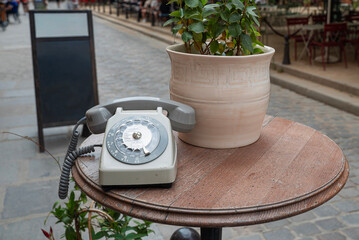 Zabytkowy telefon tarczowy na stoliku w ogródku restauracyjnym © siwyk
