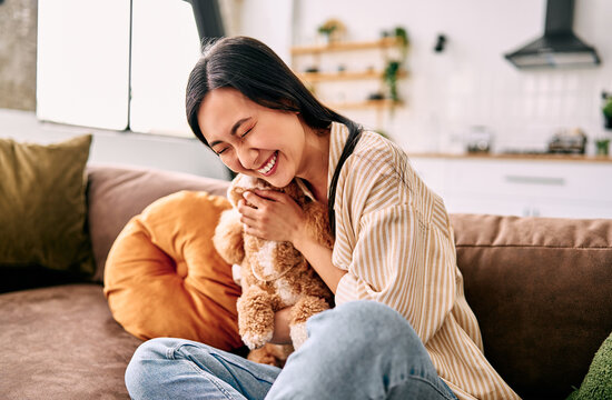 Happy woman cuddling her small dog at home.