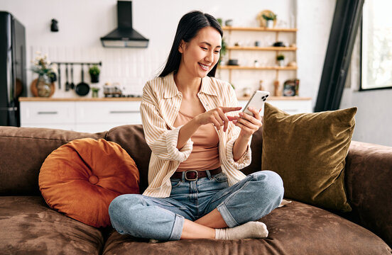 Young woman using smartphone on sofa at home.