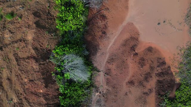 Aerial view of bauxite mining land showing red soil excavation and surrounding tropical vegetation in Indonesia.