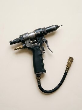 Industrial Pneumatic Rivet Gun Tool with Air Hose on Plain Background