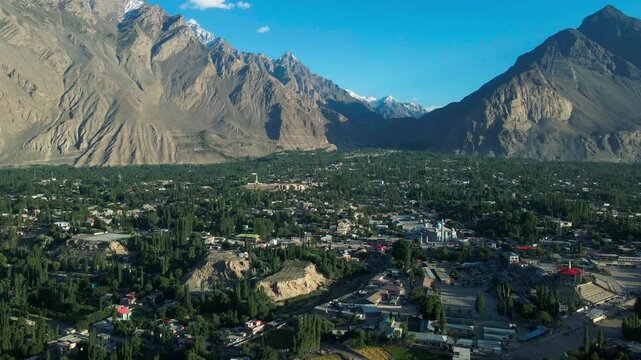 Aerial view of Skardu city nestled among mountains with lush greenery and buildings in Skardu, GB, Pakistan.