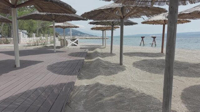 Thatched Beach Umbrellas and Wooden Deck on Sunny Seaside Beach