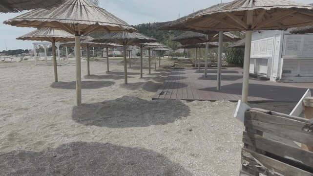 Thatched Beach Umbrellas and Wooden Deck on Sunny Seaside Beach