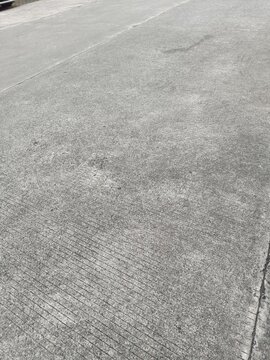 High angle view of textured grey concrete pavement with brushed linear lines and joints