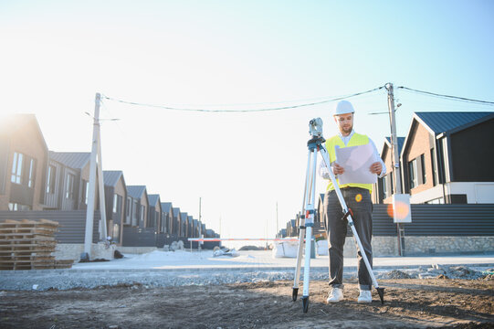 Male surveyor engineer holding blueprint at building site