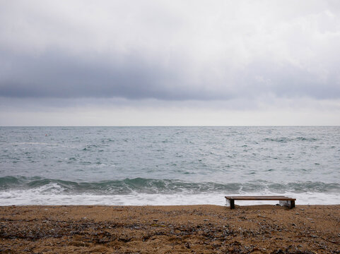 Empty bench deserted stormy Adriatic beach overcast Budva Montenegro winter