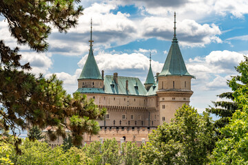Bojnice Castle turrets framed by pine branches under summer sky © pszabo