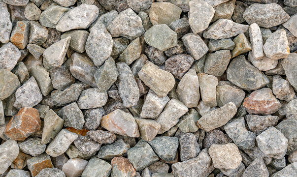 Close up of crushed stones background texture, Details in various colors, but leaning mostly towards natural grey gravel pebbles surface top view.