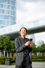 Businesswoman using smartphone in a city park near modern buildings in daytime © BGStock72