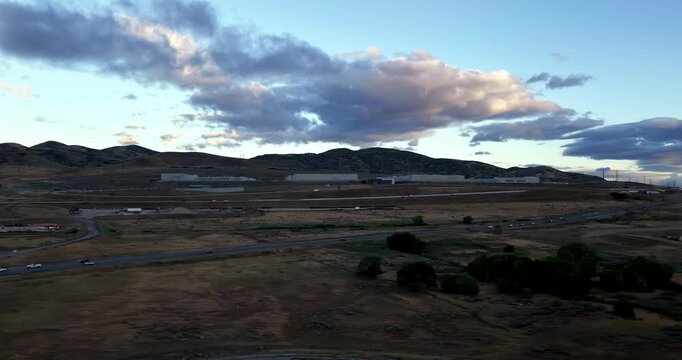Aerial view of the Utah Data Center facility situated in the arid landscape of Camp Williams, with rolling hills and a highway in the foreground, Saratoga Springs, Utah, United States.