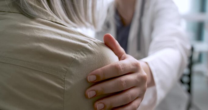Healthcare worker touching elderly patient's shoulder with compassion and talking