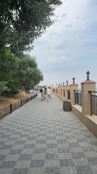 People walking along the Zolotoy Bereg embankment in Odesa, Ukraine, seaside promenade, static shot.