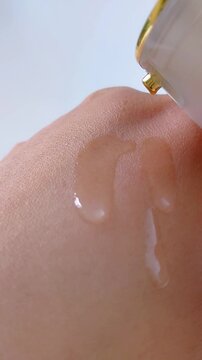 Clear cream dripping onto back of hand. Close up view. Transparent moisturizing texture for skincare or beauty concept.