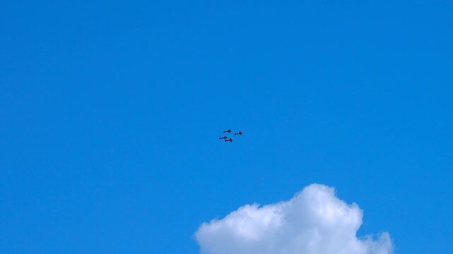 Sports planes fly in formation with smoke trails.