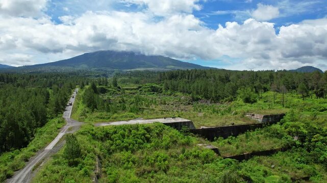 Aerial drone footage of a lava dam, in Jurang Jero area, north Yogyakarta, Sleman regency, Java island, Indonesia, with Merapi volcano behind in clouds, wild forest park