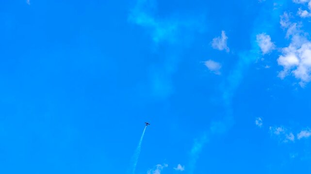 A red sports plane performing aerobatics with a smoke trail.